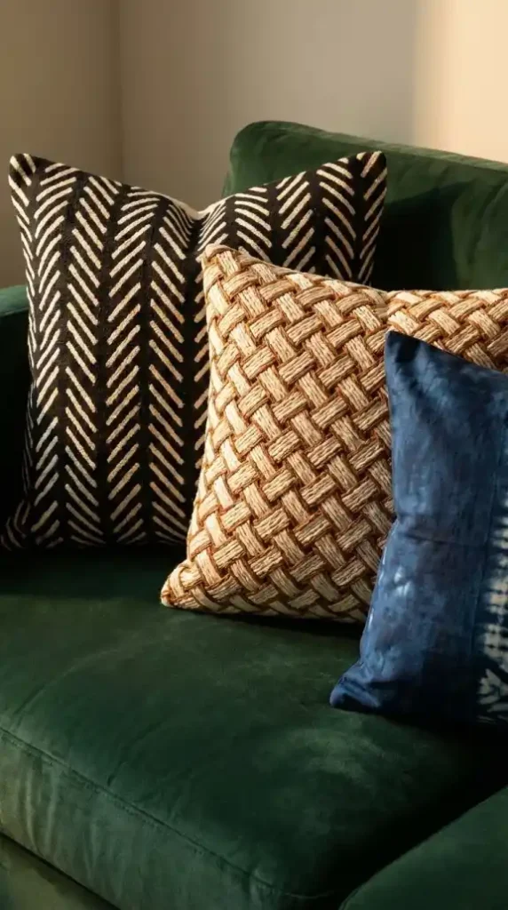 Three-African-textile-cushions-arranged-on-forest-green-velvet-sofa