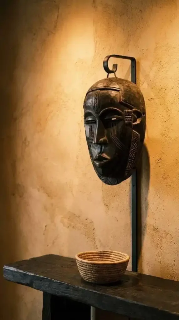 Carved-Bamileke-mask-on-museum-bracket-against-ochre-plaster-wall