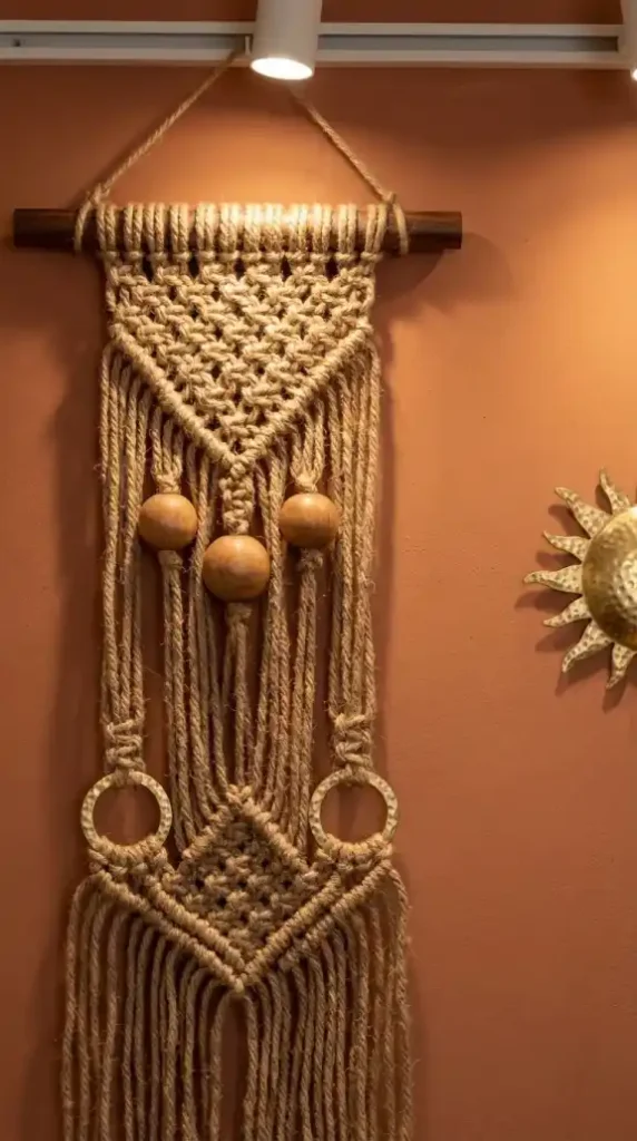Jute-cord-macramé-with-wooden-beads-and-brass-rings-on-plaster-wall