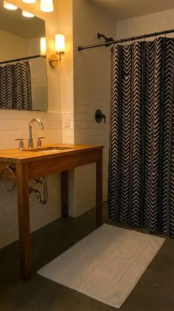mud cloth shower curtain in black and cream geometric chevron being hung from a matte black curtain rod in an Afro Bohemian bathroom